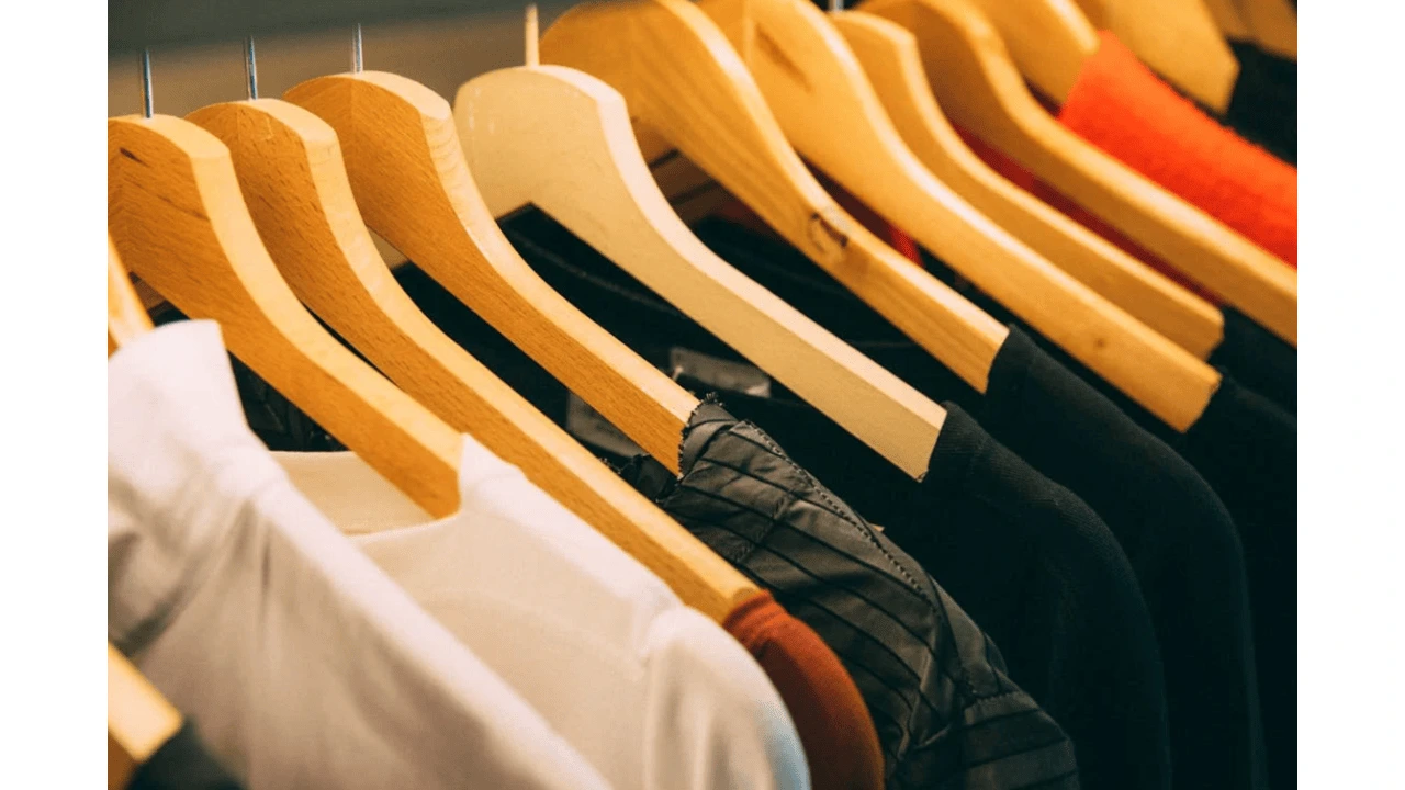 A set of t-shirts hanging on wooden hangers, displaying a variety of colors and styles