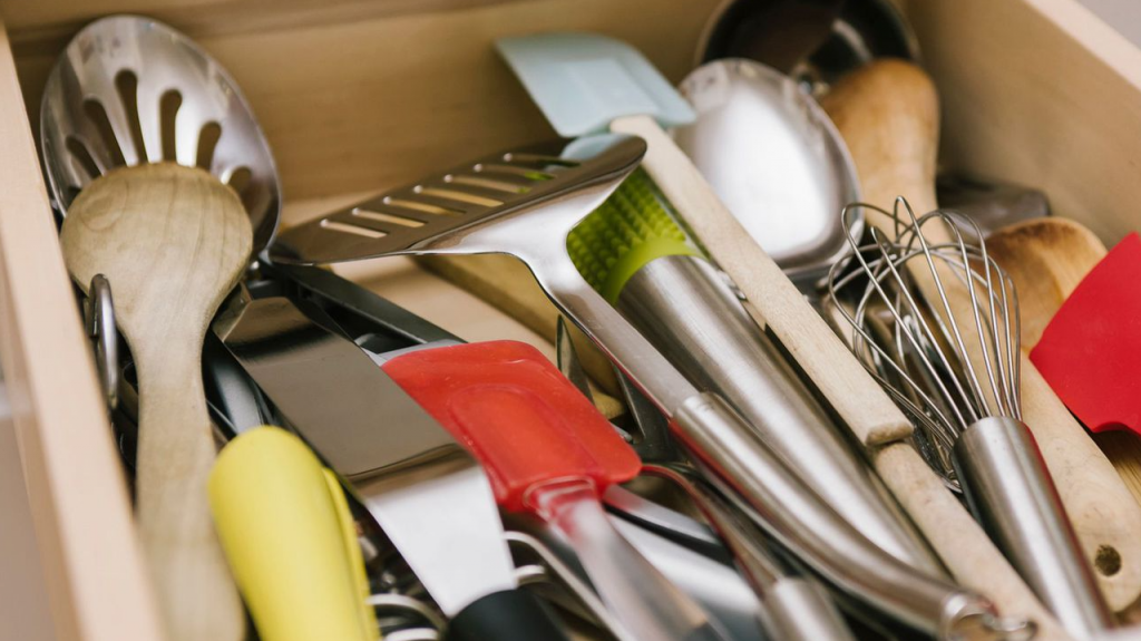 A collection of wholesale kitchen utensils, including spatulas, whisks, and ladles, arranged on a wooden countertop